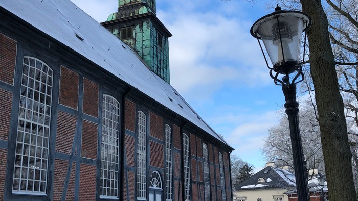Schneebedeckte Straße mit Kirche und Bänken