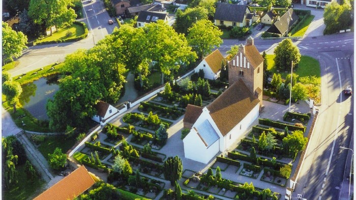En hvid kirke med tårn og omgivelser, beliggende i en grøn og træfattig bydel.