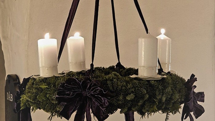 En hængende kandleholder med grønne blomster og sorte bælter.