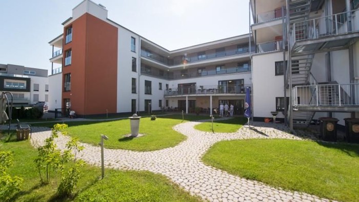 Modernes Wohngebäude mit Innenhof und gepflegtem Grün.