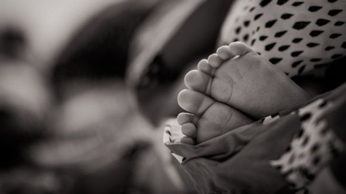 Ein Baby liegt auf einer Decke, die Füße sind deutlich zu sehen.