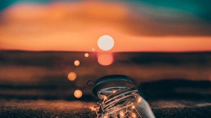 Ein Glas liegt auf dem Boden vor einem Sonnenuntergang