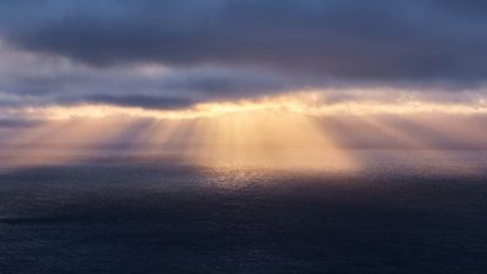 Ein dramatischer Himmel mit Sonnenstrahlen, die durch dunkle Wolken brechen
