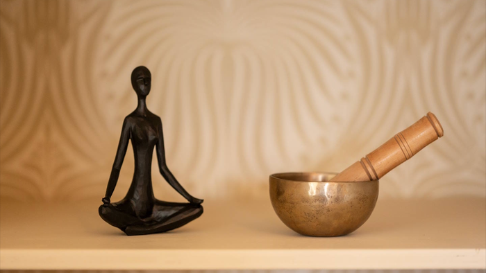 Une statuette de femme en méditation et une coupelle de sonnerie sur une étagère