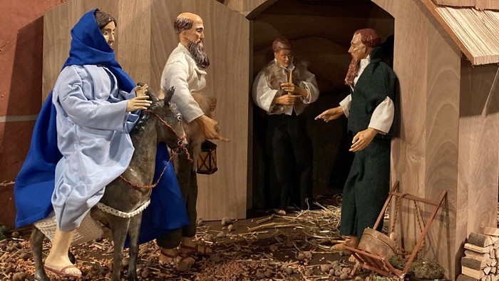 Eine Krippe mit Figuren und Tieren vor einer Holzhütte