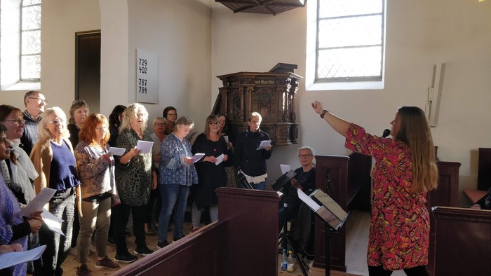 Kvindelig dirigent leder et kor i en kirke
