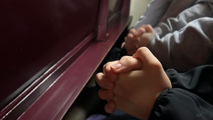 To par foldede hænder ved violet kirkebænk