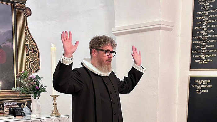 Mand i svart kapittel i kirke.