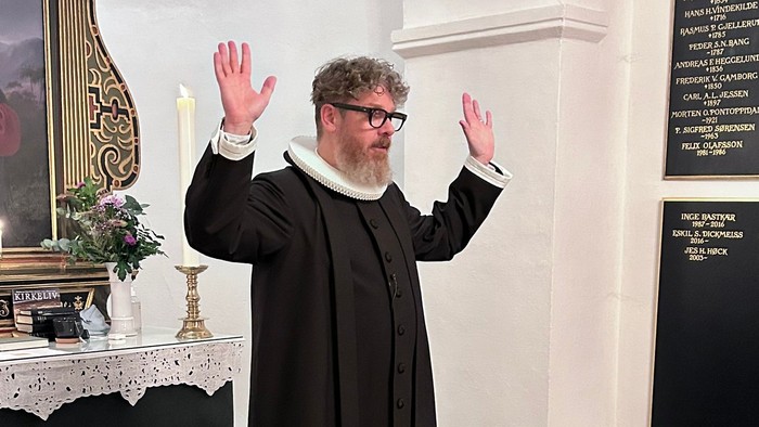 Mand i svart kapittel i kirke.