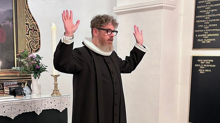 Mand i svart kapittel i kirke.