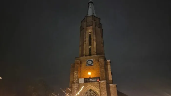 Ein beleuchteter Kirchturm bei Nacht mit Uhr und Weihnachtslichtern