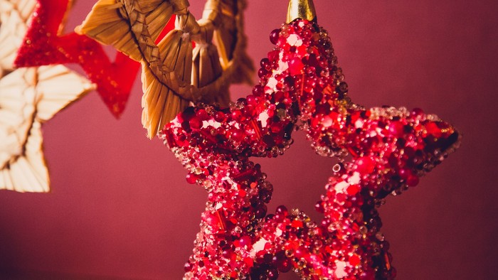 En rød glitrende stjerne hænger i forgrunden, omgivet af andre juledekorationer.