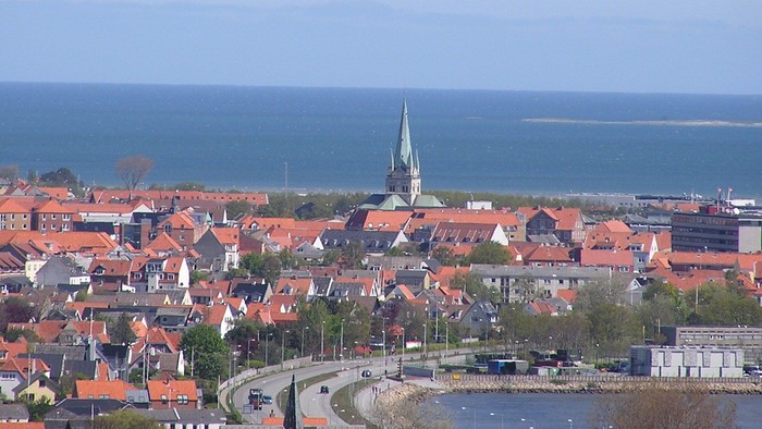 En kystby med røde tagtegn og en kirke tæt på havet