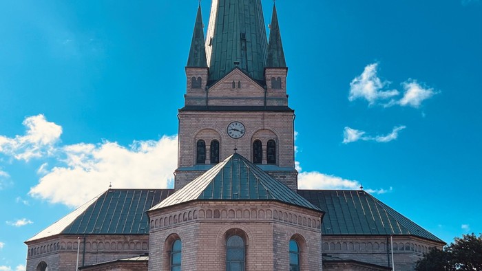 Gammel kirke med spire og blå himmel