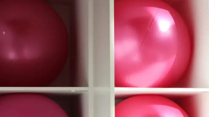 Vier glänzende rote Christbaumkugeln, in einem Raster auf weißem Hintergrund angeordnet.