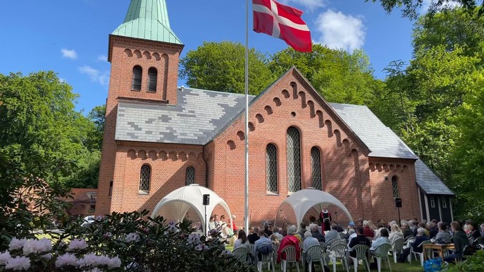 Kirkeservice ude med flag og folkemængde