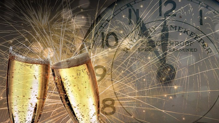 Zwei Champagnergläser stoßen auf Silvesterfeuerwerk vor Uhr.
