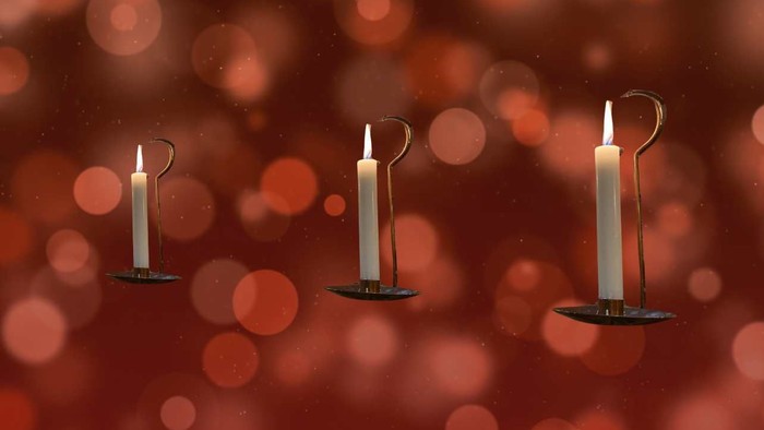 Fire tændte stearinlys på række mod en mørkerød baggrund med bokeh-effekt.