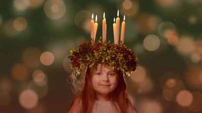 En ung pige bærer en krans af lys og grønt, stående foran en sløret, festlig baggrund.
