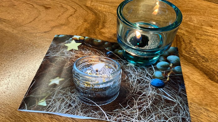 Zwei brennende Kerzen auf einem Tisch mit Naturmotiven