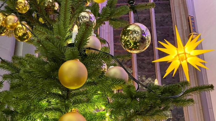 Ein Weihnachtsbaum mit goldenen Kugeln und einer leuchtenden Sternspitze