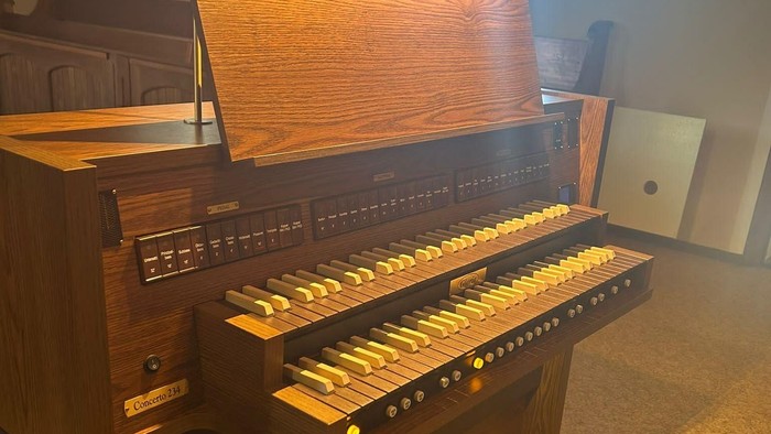 Ein hölzernes Harmonium mit zwei Klaviaturen in einem Raum