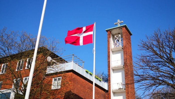 Dansk flag ved kirke med klokketårn