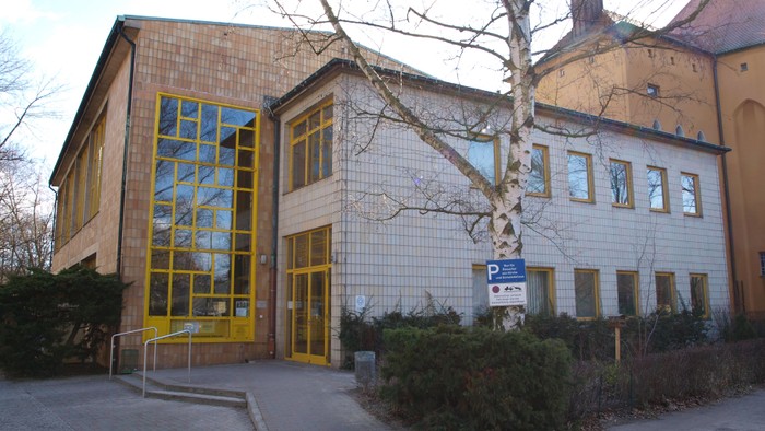 Gelbes Gebäude mit großen Fenstern und Baum davor