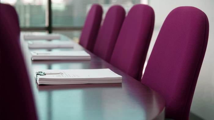 En konferencebord med rødstøle og papirer.