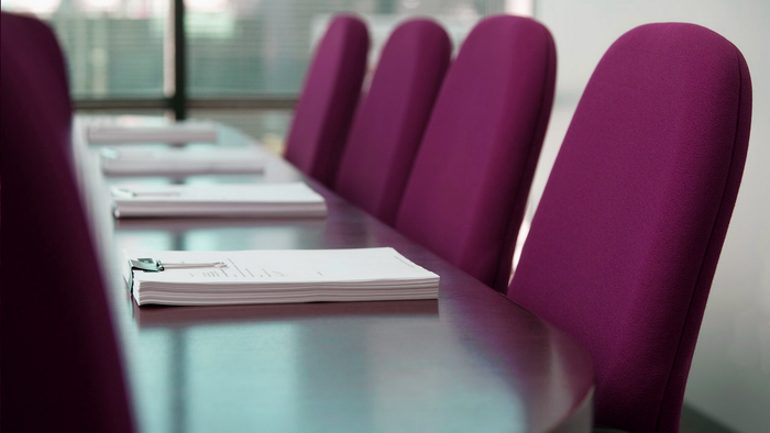 En konferencebord med rødstøle og papirer.