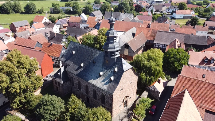 Luftaufnahme einer Stadt mit einer großen Kirche und umliegenden Häusern.