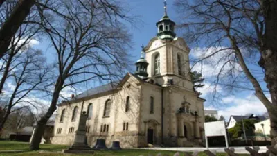 Alte Kirche mit hohem Turm und nackten Bäumen im Vordergrund