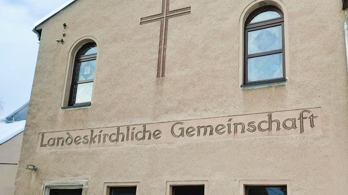 Das Gebäude trägt ein Kreuz und die Aufschrift 
