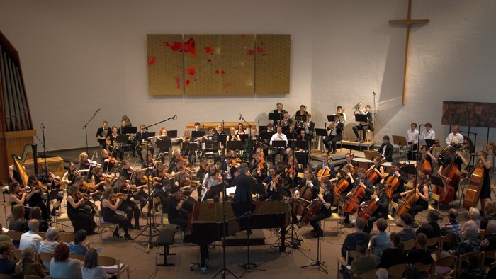 Ein Orchester spielt in einer Kirche vor einem Publikum