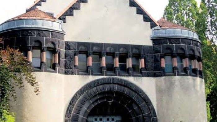 Das Bild zeigt ein altes, weißes Gebäude mit Türmen und einem blauen Tor.