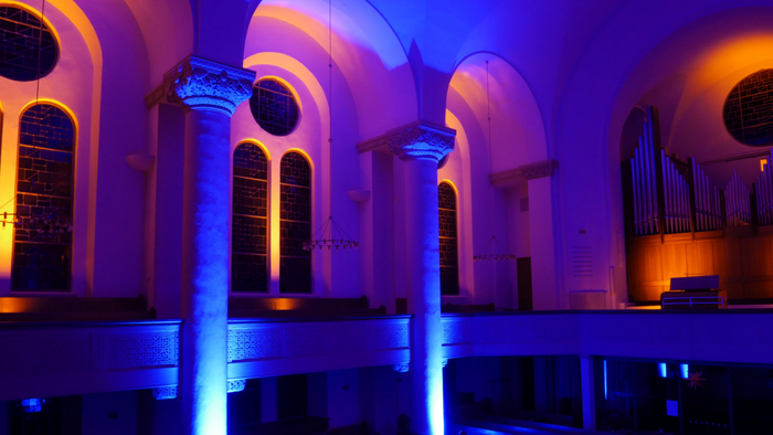 Bunte Beleuchtung in einem Kircheninneren mit Säulen und Orgel