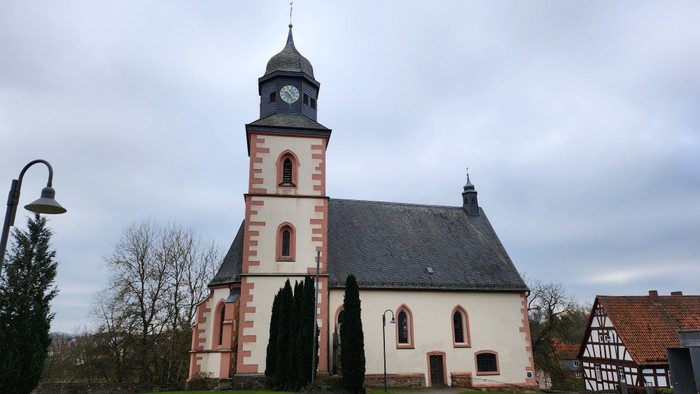 Kirchengebäude mit Uhrturm und rot-weiß gestreifter Fassade