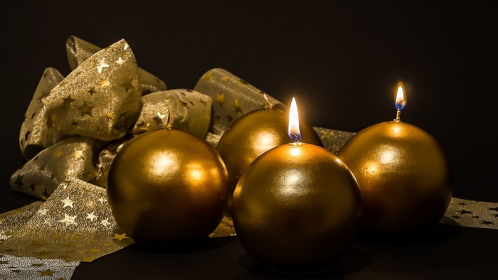 Goldene Kerzen und Christbaumkugeln auf schwarzem Hintergrund