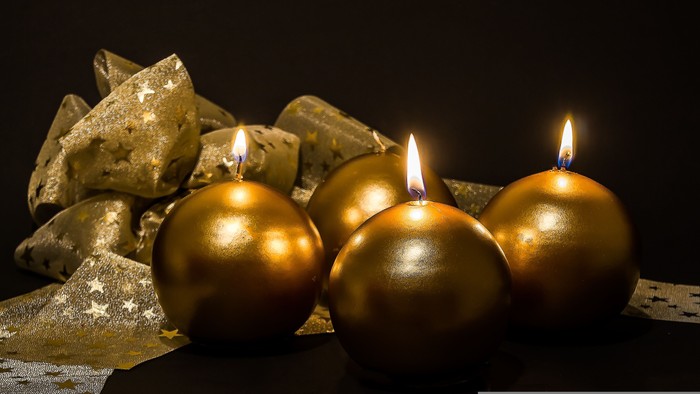 Goldene Kerzen und Weihnachtskugeln auf schwarzem Hintergrund