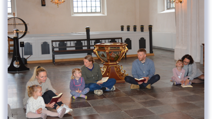 Familie, der læser sammen i et stort rum.