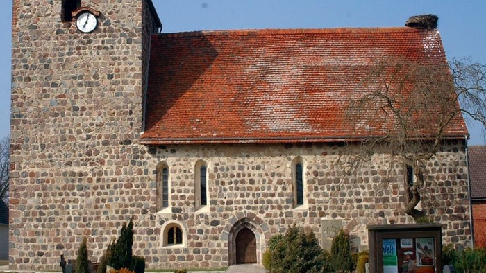 Alte Kirche mit Turm und Zifferblatt unter blauem Himmel
