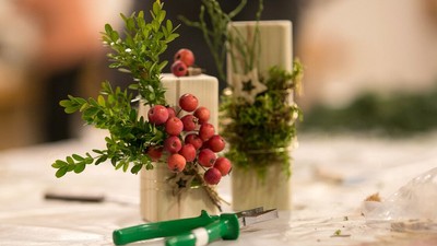 Zwei Topfpflanzen mit roten Beeren und grüne Schere auf Tisch