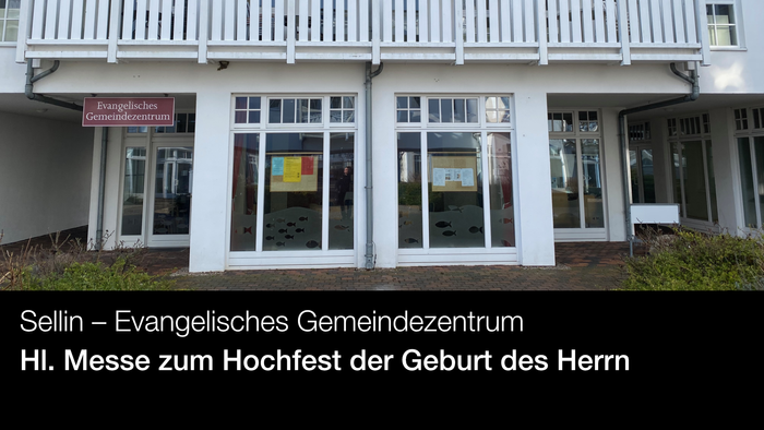 Weißes Gebäude mit großen Fenstern und einem Schild