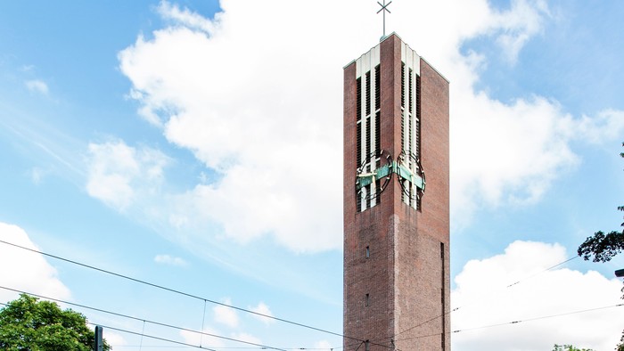 Ein hohes Ziegelgebäude mit Uhrturm an einer belebten Straße