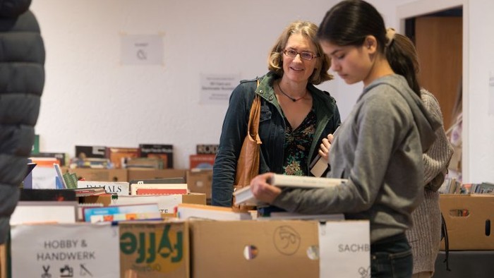 Zwei Frauen stöbern in Büchern und Materialien auf einer gemeinschaftlichen Hobby- und Bastelveranstaltung.
