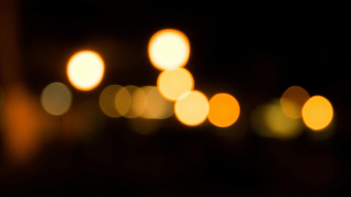 Verwischte Lichter erzeugen ein warmes, leuchtendes Muster vor einem dunklen Nachthimmel.