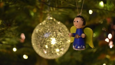 Ein Weihnachtsbaum mit einem Engel-Christbaumschmuck und einer großen, durchsichtigen Kugel.