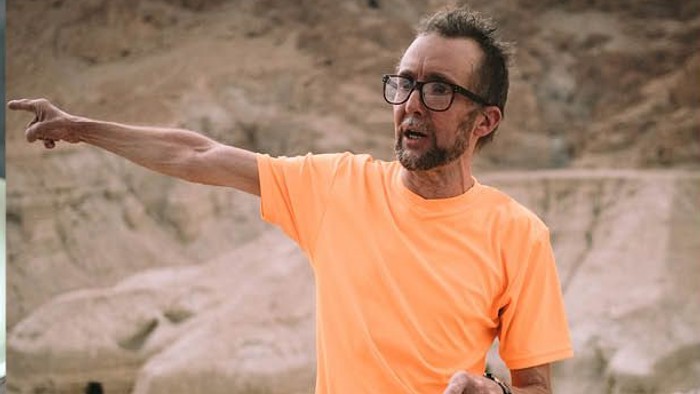 Mand i orange skjorte, der peger på kaffekopper.