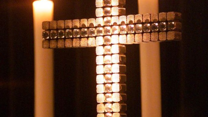 Kreuz mit Kerzen, die auf beiden Seiten entzündet sind.