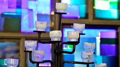 Mehrarmiger Kerzenhalter mit weißen Kerzen vor buntem Hintergrund